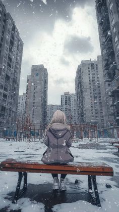 a woman sitting on top of a bench in front of tall buildings and snow covered ground