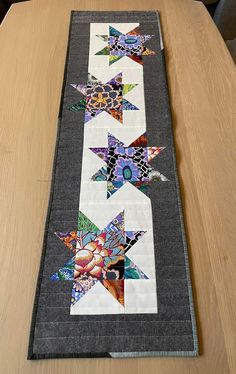 a table runner made out of quilts on top of a wooden table