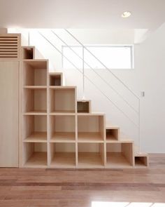 an empty room with some shelves on the wall and stairs to the second floor in it