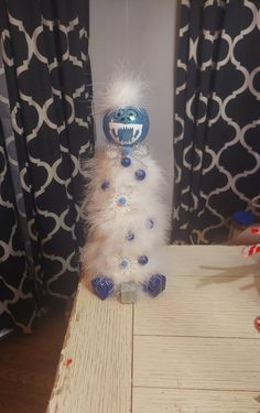 a white and blue decoration sitting on top of a wooden table next to a window