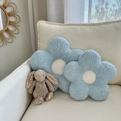 a stuffed animal sitting on top of a white couch next to a blue flower pillow