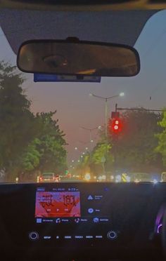 the dashboard of a car at an intersection with traffic lights and trees in the background