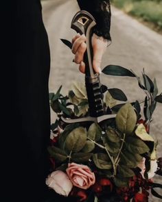 Bride in a black wedding dress holding a bouquet of pink and red flowers with lots of leaves downward by a sword hilt on a path. Lotr Wedding, Forest Theme Wedding, Pagan Wedding, Viking Wedding, Enchanted Forest Wedding, Medieval Wedding