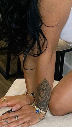 a woman with tattoos on her arm and leg sitting on a bed next to a laptop