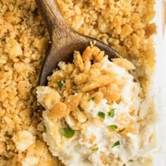 a casserole dish filled with mashed potatoes and green onions, topped with a wooden spoon