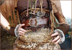 a woman wearing a brown outfit and holding a fur purse with her hands in the pockets