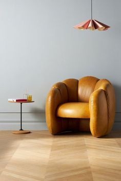 a brown leather chair sitting on top of a hard wood floor next to a table