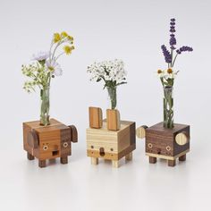 three vases with flowers in them sitting next to each other on a white surface