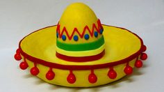 a yellow sombrero sitting on top of a white table next to red balls