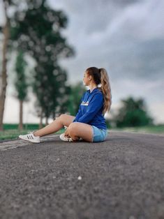 a young woman sitting on the side of a road