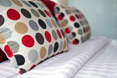 two pillows on top of a bed with white and red sheets