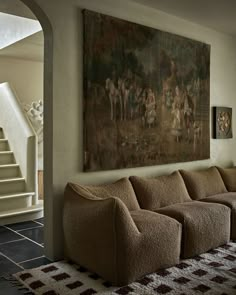 a living room filled with furniture and a large painting hanging on the wall above it