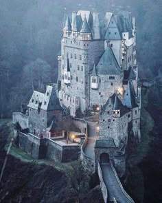 an aerial view of a castle in the foggy day with its lights on and stairs leading up to it