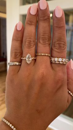 a woman's hand with three different rings on her fingers and one is holding the other