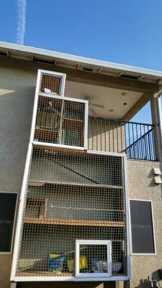 a bird cage in front of a building with stairs leading up to the second floor