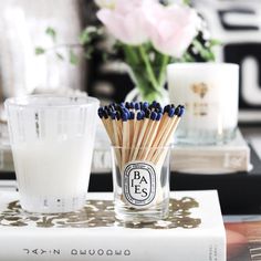 a glass filled with matches sitting on top of a table next to a vase full of flowers