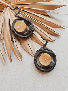 two candles sitting on top of a table next to palm leaves