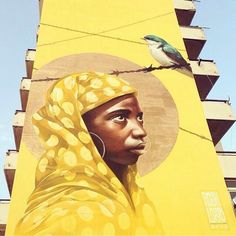 a painting of a woman with a bird on her head next to a yellow building