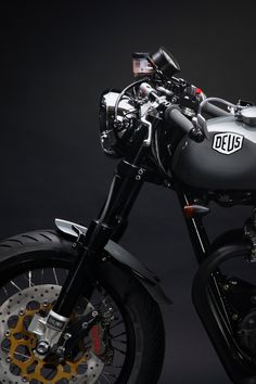 a black and silver motorcycle parked on top of a dark floor with yellow spokes