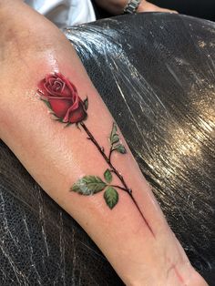 a red rose with green leaves on the arm