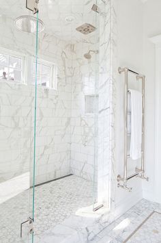 an instagramted photo of a bathroom with white marble walls and floors, including a walk - in shower