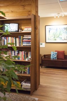 an open book shelf with books on it in a living room next to a couch