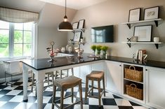 a kitchen with black and white checkered flooring, two bar stools in the center