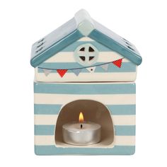 a small blue and white house with a lit candle in the center on a white background