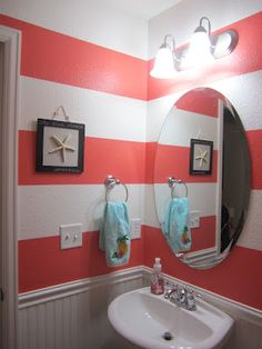 a bathroom with red and white stripes on the wall, sink and mirror in it