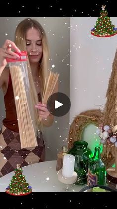 a woman is holding up some noodles in front of a christmas tree and other decorations