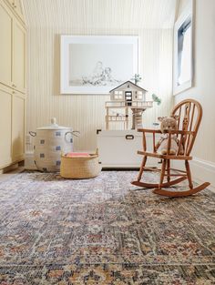 a rocking chair sits in the corner of a room with a rug on the floor