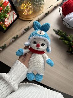 a hand holding a small crocheted stuffed animal in the shape of a bunny