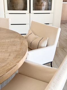 a wooden table sitting next to two white chairs