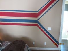 a room with a bed and a wall painted in red, white, and blue