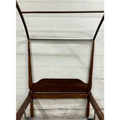 a wooden bed frame sitting against a white brick wall with wheels on each side and an iron bar attached to the headboard