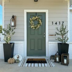 a front door with two planters and a wreath on the porch next to it