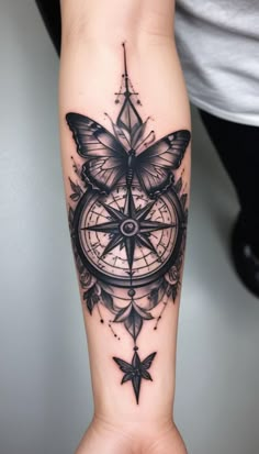 a woman's arm with a butterfly and compass tattoo on it