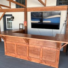 a large wooden bar in front of a tv mounted on the side of a building