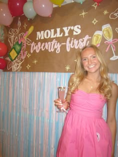 a woman in a pink dress holding a glass of wine and standing next to a sign that says moly's beauty - first