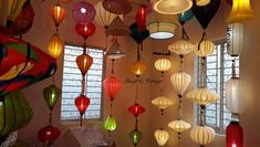 many colorful lanterns hanging from the ceiling in a room