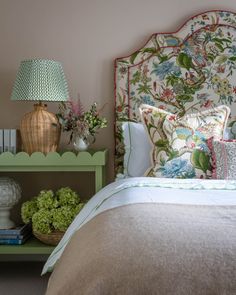 a bedroom with a bed, nightstand and lamp on the side table in front of it