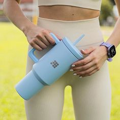 a woman in tights holding a blue water bottle with her hands on her hip