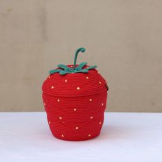 a red strawberries covered in gold dots on a white tablecloth with a green handle