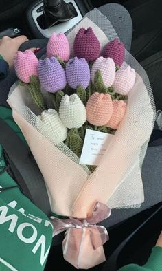 a bunch of crocheted flowers sitting in the back seat of a car with someone holding it