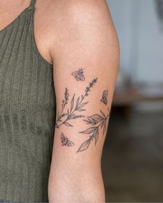 a woman's arm with flowers and butterflies tattooed on the left side of her arm