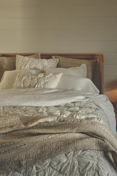 an unmade bed with white linens and pillows on top of it in a bedroom