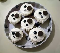 cupcakes decorated with white frosting and chocolate eyes are on a platter