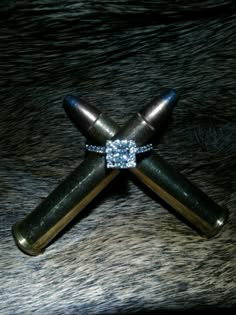 a diamond ring sitting on top of a black piece of animal fur with two wooden sticks sticking out of it's center