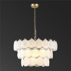 a chandelier hanging from the ceiling with white glass petals and gold trimmings