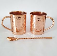 two copper mugs with spoon on white background